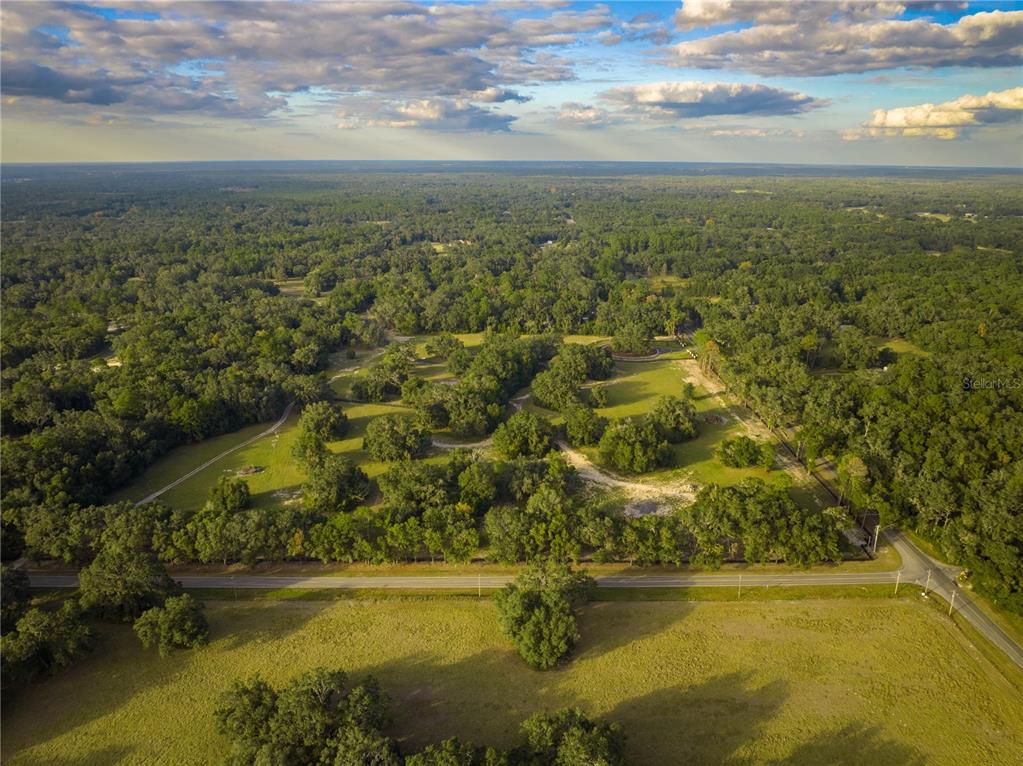 An aerial view shows a large, wooded plot of land bordering a paved road — 17287 SW 11 COURT, NEWBERRY, FL