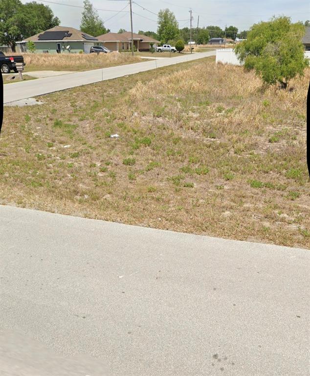 A vacant, grassy residential lot sits between a paved road and a white fence — TBD DOGWOOD DR CIRCLE, OCALA, FL