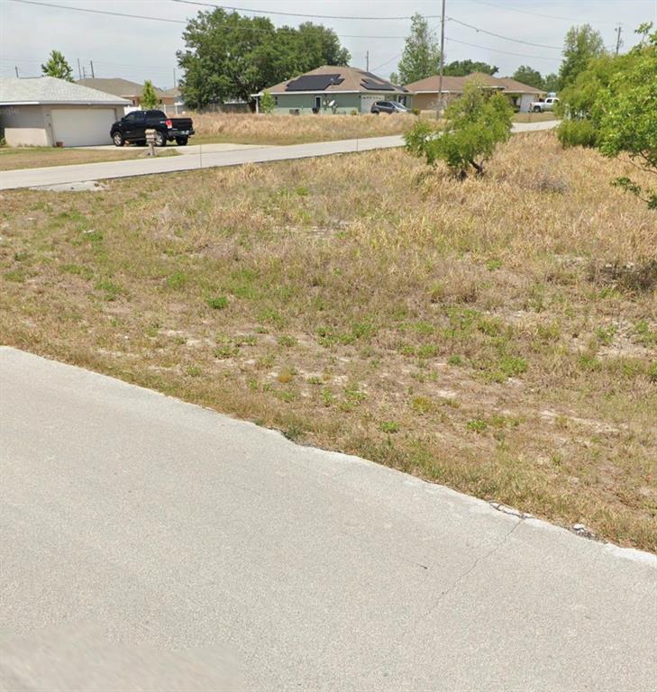 A vacant, grassy residential lot sits between paved roads with neighboring houses in the background — TBD DOGWOOD DR CIRCLE, OCALA, FL