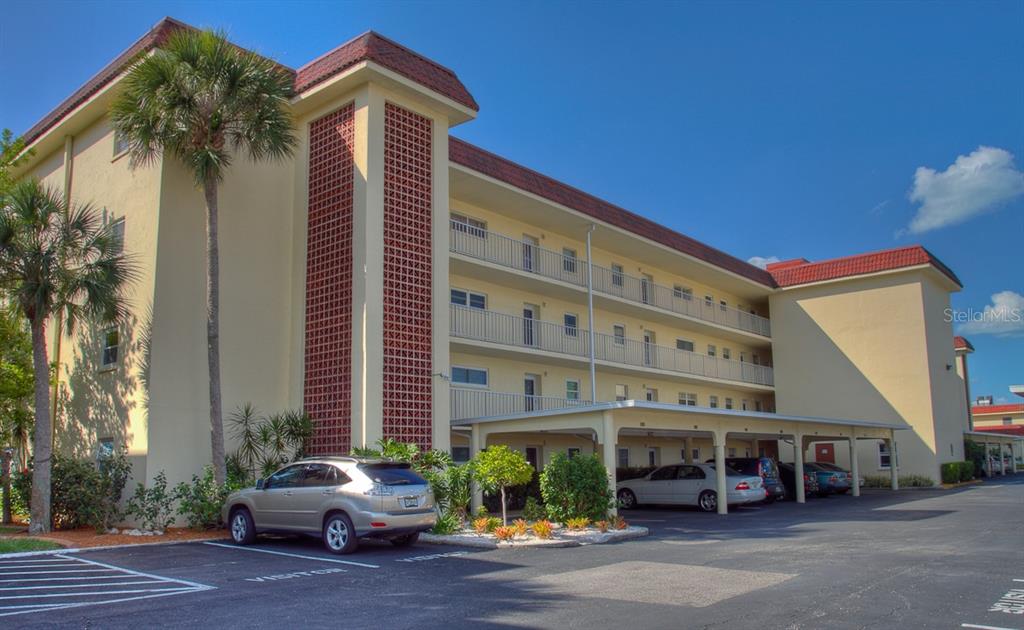 A multi-story apartment building with a covered parking area and decorative brick facade — 1250 N PORTOFINO DRIVE UNIT 107MAR, SARASOTA, FL