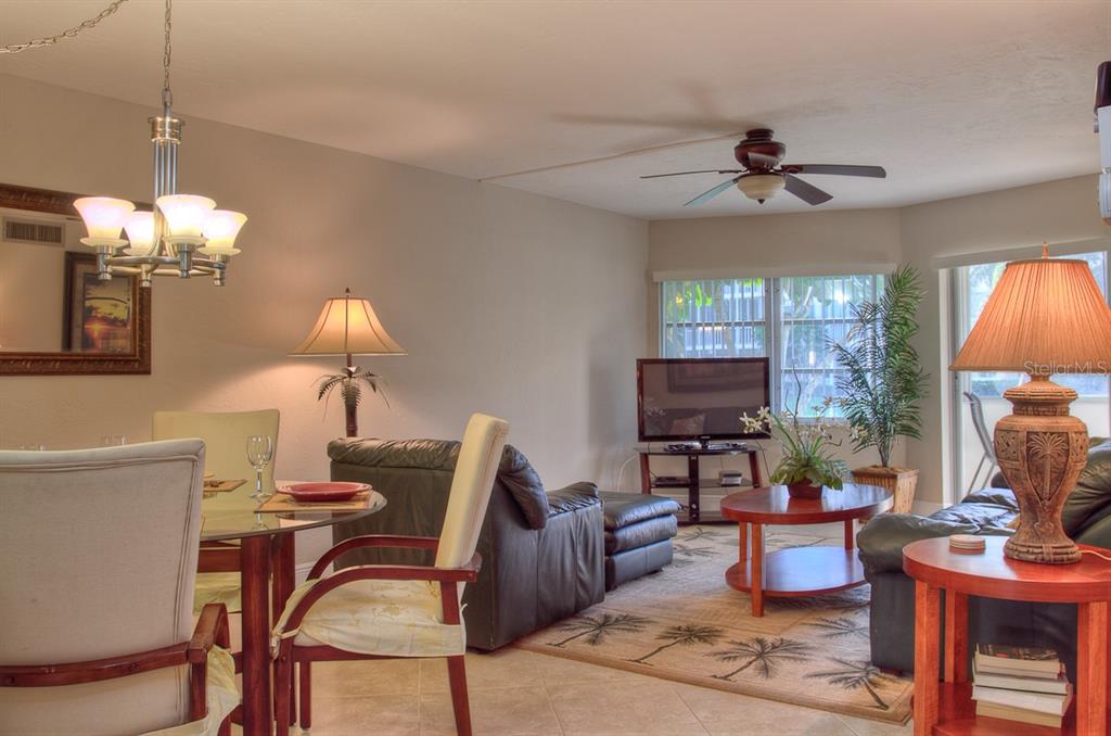A living and dining area featuring a glass table, leather furniture, and a ceiling fan — 1250 N PORTOFINO DRIVE UNIT 107MAR, SARASOTA, FL