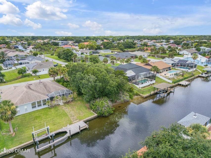 An aerial view shows waterfront houses with screened-in pools along a canal — 9 N CHRISTOPHER COURT, PALM COAST, FL