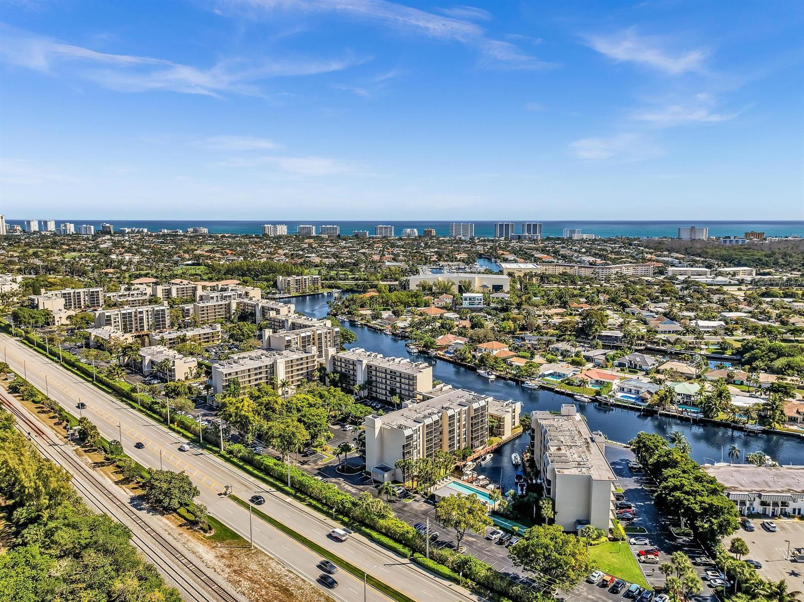 An aerial view shows a coastal neighborhood with apartment complexes, a canal, and a highway — 100 Royal Palm Way # 303, Boca Raton FL 33432, BOCA RATON, FL