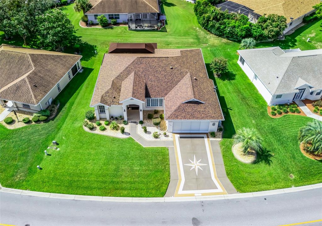 An aerial view shows a single-story house with a brown roof and a decorative driveway — 11768 SE 176TH PLACE ROAD, SUMMERFIELD, FL