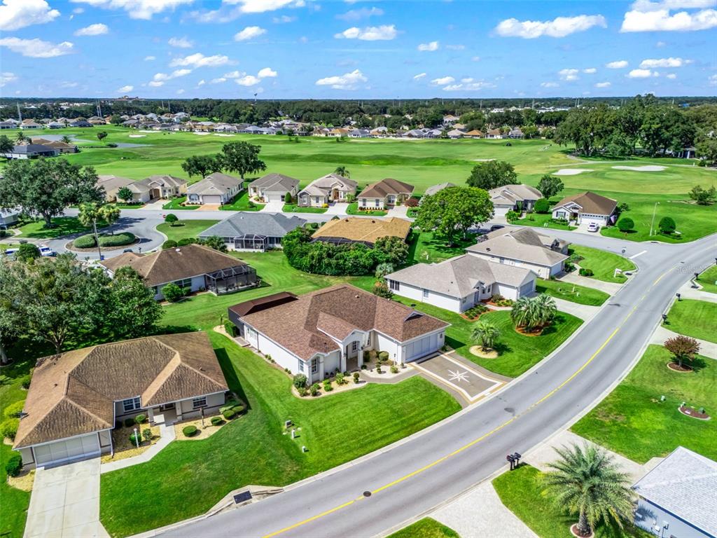 An aerial view shows suburban houses with brown roofs situated along a road near a golf course — 11768 SE 176TH PLACE ROAD, SUMMERFIELD, FL