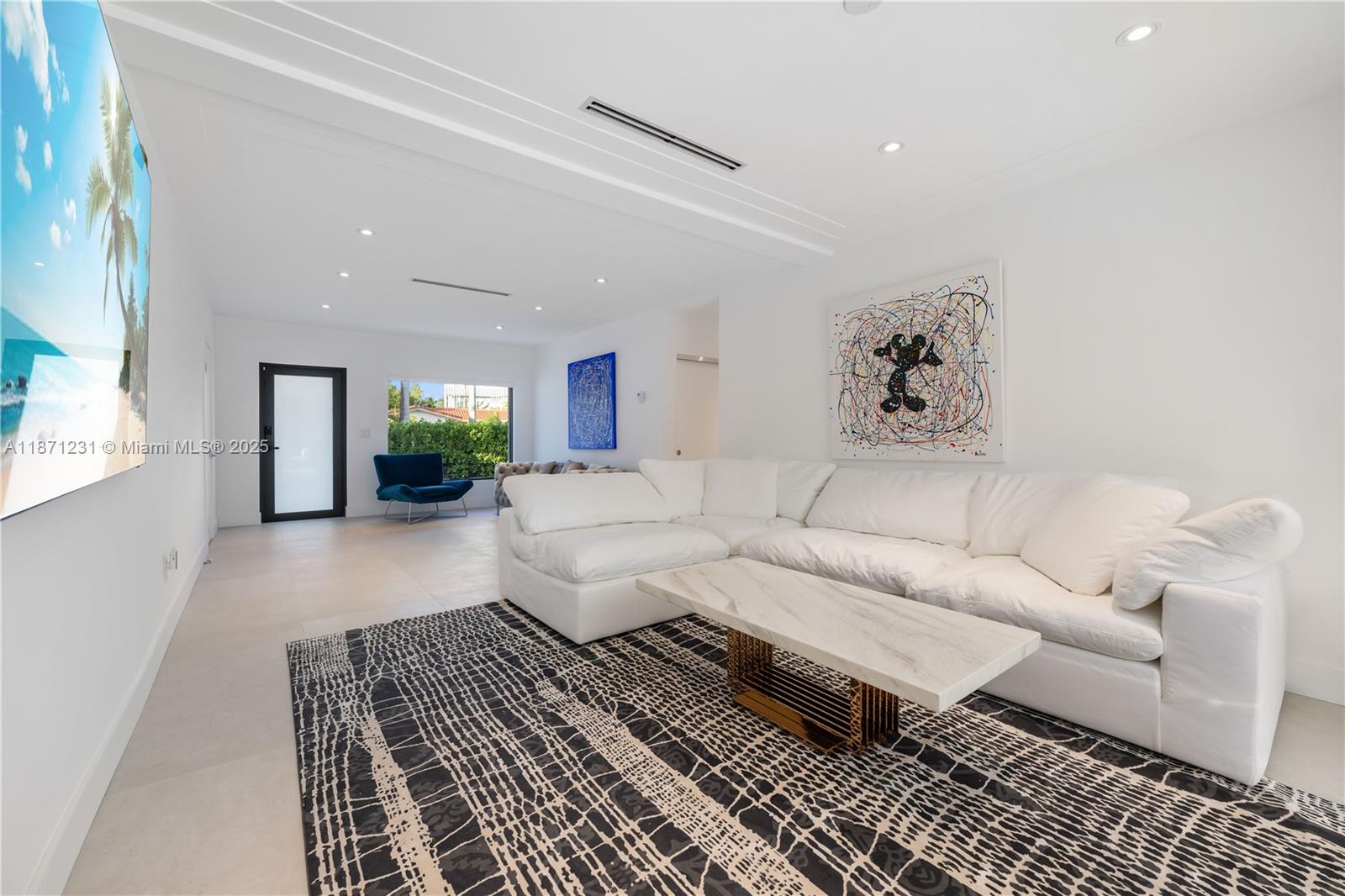 A modern living room features a white sectional sofa, a marble coffee table, and artwork — 900 W 47th Ct, Miami Beach FL 33140, MIAMI BEACH, FL
