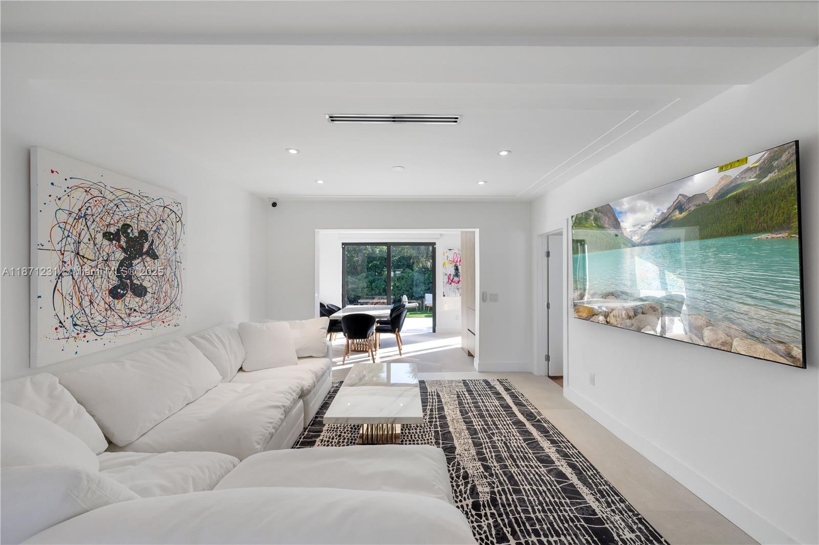 A modern living room features a white sectional sofa, a patterned rug, and a large television — 900 W 47th Ct, Miami Beach FL 33140, MIAMI BEACH, FL