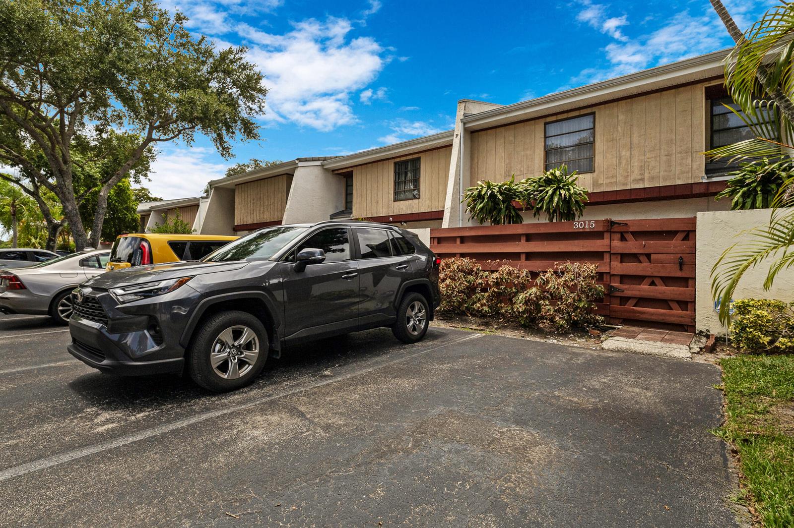 A dark gray SUV is parked in front of a two-story townhouse with wood siding — 3015 Oaktree Lane Unit 277, Hollywood FL 33021, HOLLYWOOD, FL
