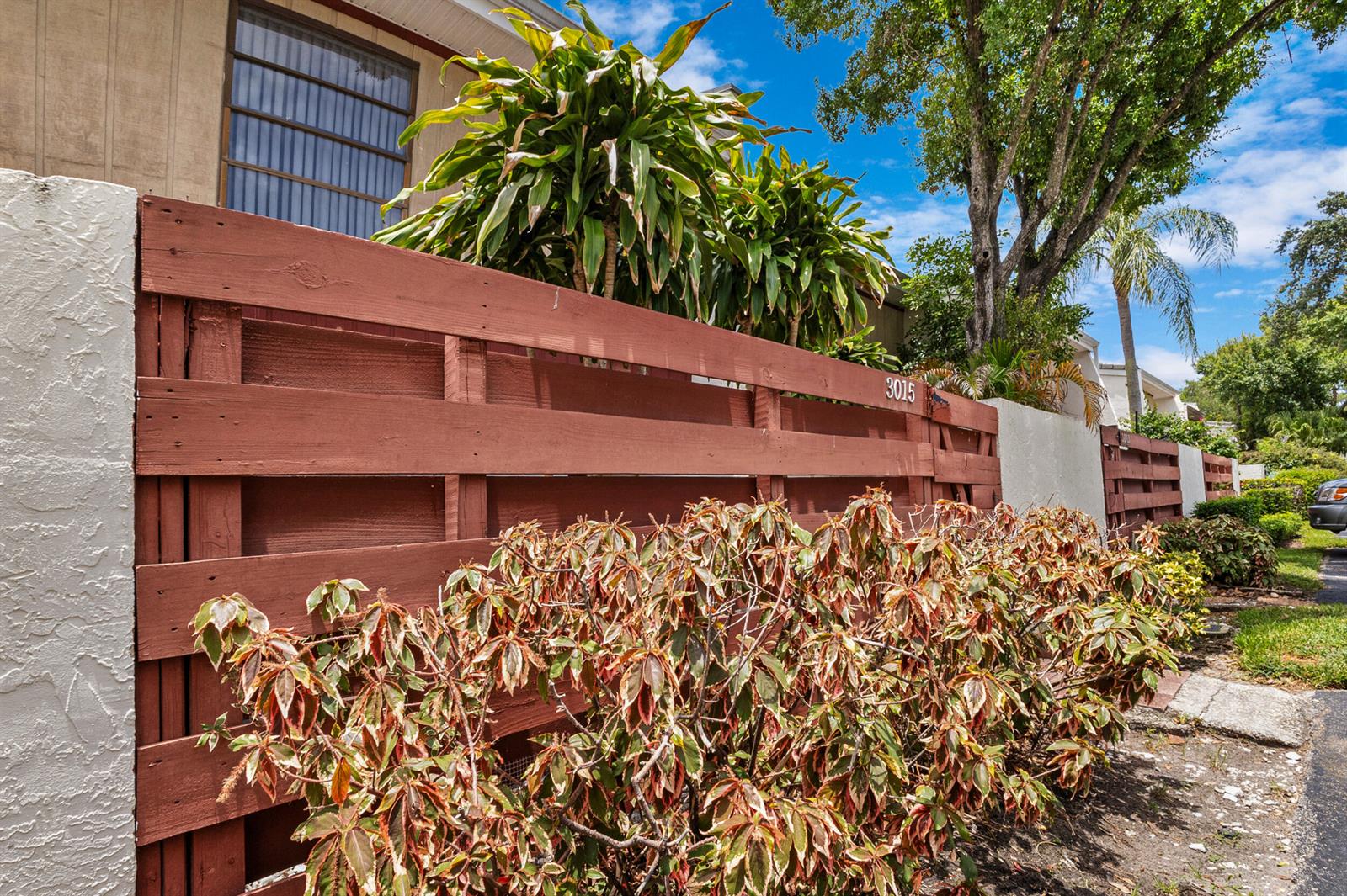 A wooden fence with the number 3015 stands in front of a house and landscaping — 3015 Oaktree Lane Unit 277, Hollywood FL 33021, HOLLYWOOD, FL