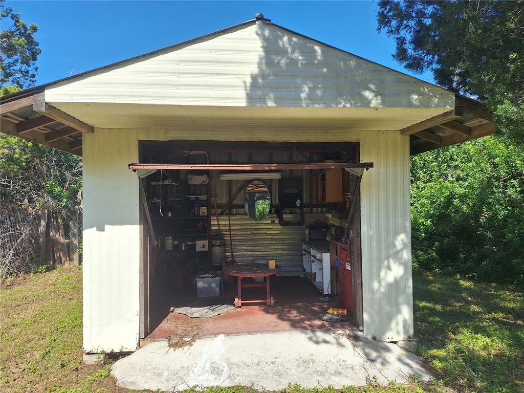 A detached shed with a metal exterior and an open garage door revealing a workspace — 6501 WERNER AVENUE, NEW PORT RICHEY, FL