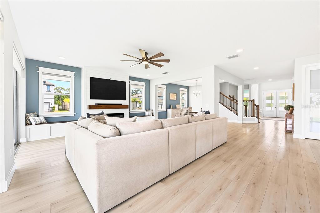 A spacious living room features a large sectional sofa, light wood flooring, and a fireplace — 2234 MAROON FLAME COURT, OVIEDO, FL