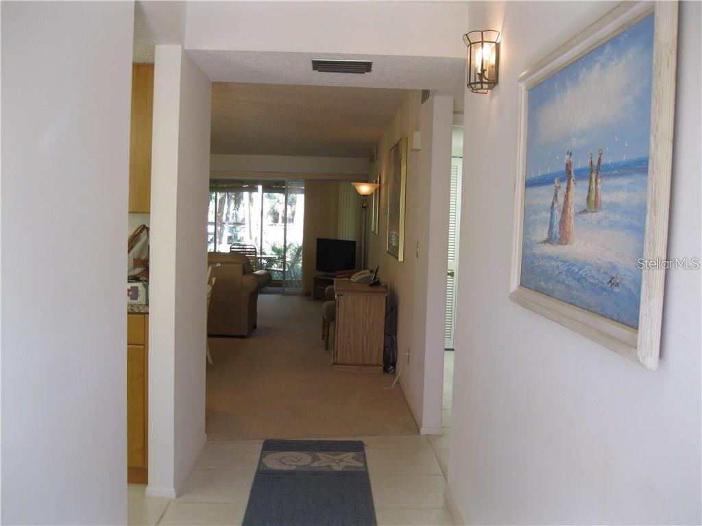 A tiled entryway leads into a carpeted living area with a view of a patio — 4397 LONGMEADOW UNIT 35, SARASOTA, FL