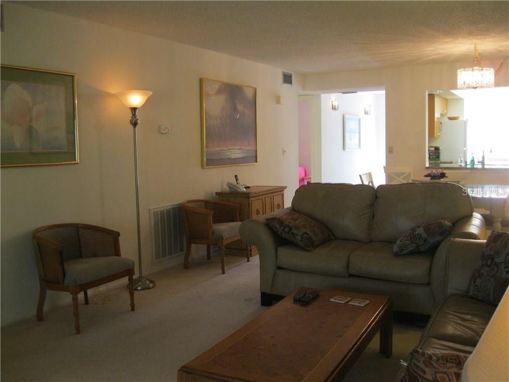 A living room features beige carpet, a leather sofa, a coffee table, and two wooden chairs — 4397 LONGMEADOW UNIT 35, SARASOTA, FL
