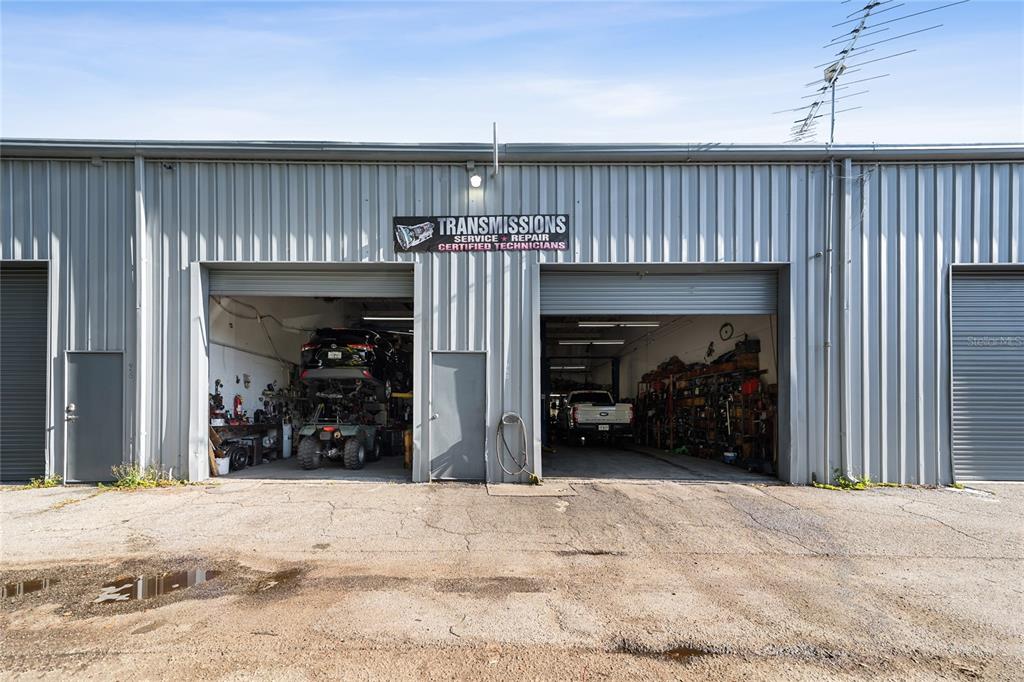 The exterior of a commercial building features two open garage bays for automotive repair — 960 E CARROLL STREET, KISSIMMEE, FL