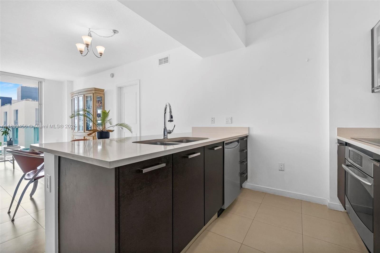 A modern kitchen features a dark wood island with a sink and stainless steel appliances — 333 NE 24th St # 812, Miami FL 33137, MIAMI, FL