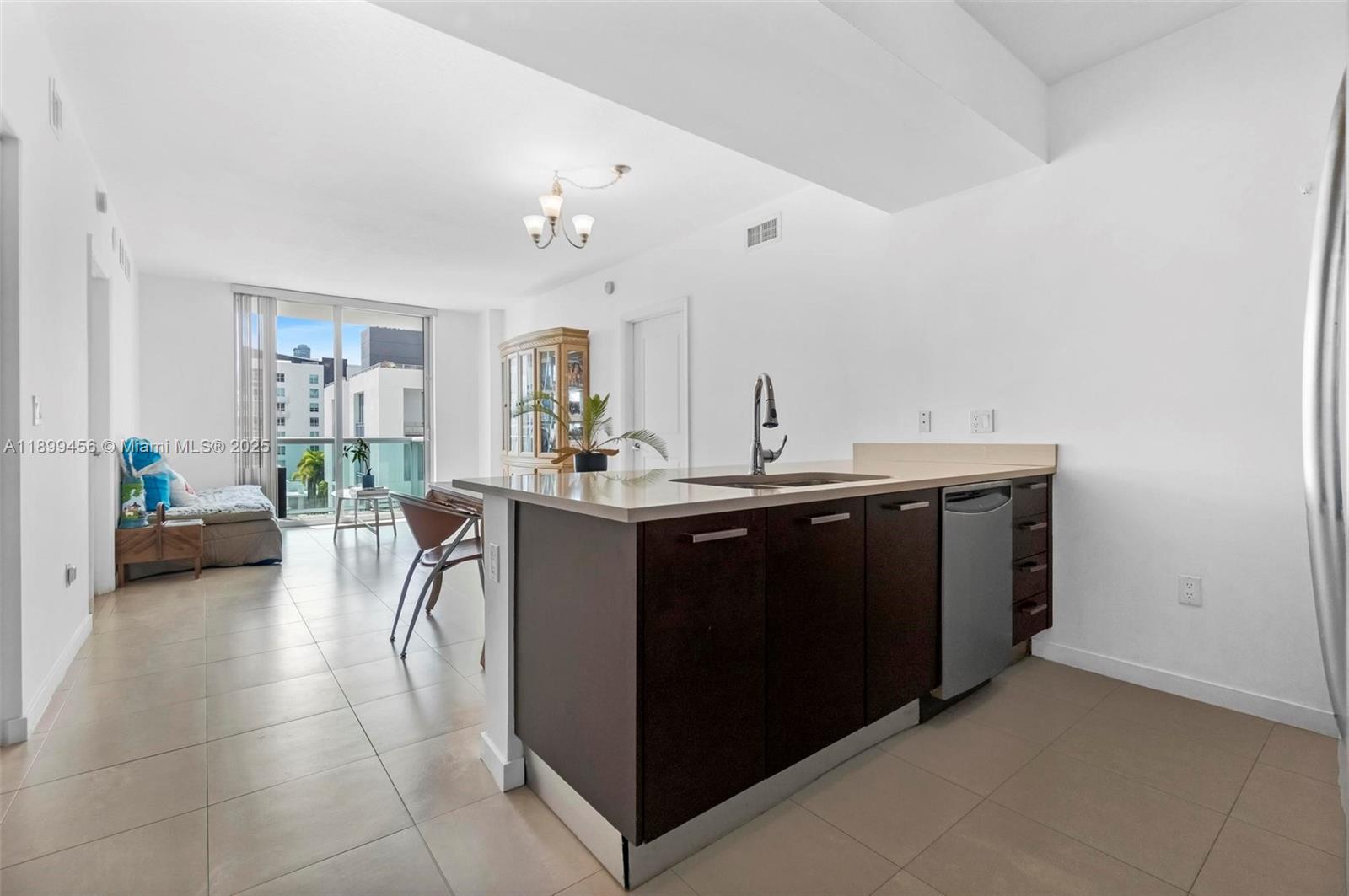 A kitchen island with dark cabinets and a sink sits in an open-concept living area — 333 NE 24th St # 812, Miami FL 33137, MIAMI, FL