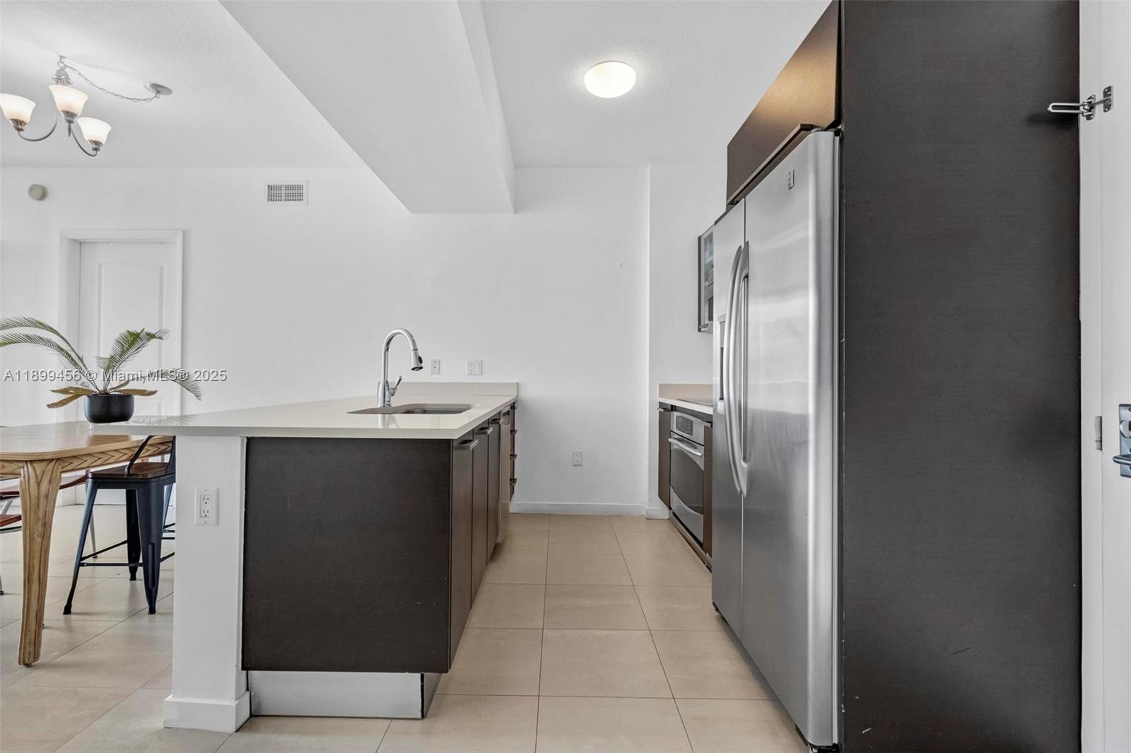 A modern kitchen features dark wood cabinetry, stainless steel appliances, and a light-colored countertop — 333 NE 24th St # 812, Miami FL 33137, MIAMI, FL