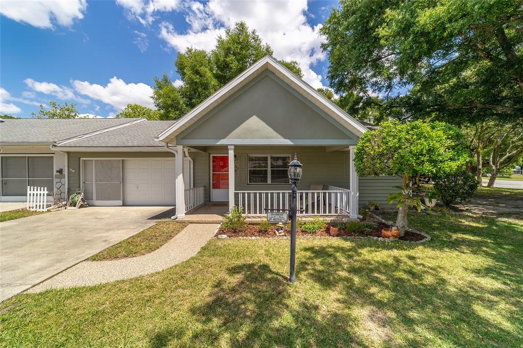 A single-story home with a covered front porch, a concrete driveway, and a small lawn — 8625 SW 94 LANE UNIT G, OCALA, FL