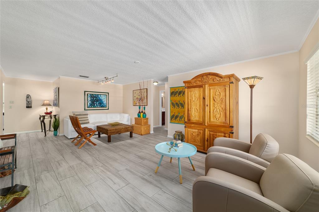 A living room features light-colored wood-look tile flooring, a white sofa, and a wooden armoire — 8625 SW 94 LANE UNIT G, OCALA, FL