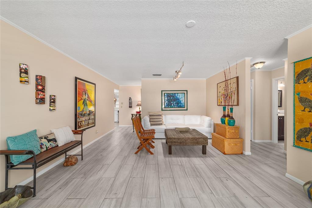 A living room with light wood-look flooring, a white sofa, and a wooden bench — 8625 SW 94 LANE UNIT G, OCALA, FL