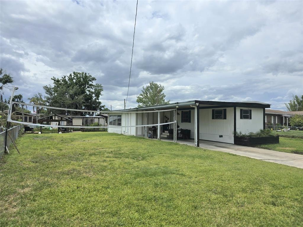 A single-story mobile home with a carport and a volleyball net in the yard — 2936 N PALM CIRCLE, HAINES CITY, FL