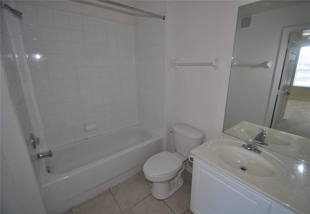 A bathroom features a white bathtub with a shower, a toilet, and a vanity sink — 588 BRANTLEY TERRACE WAY UNIT 305, ALTAMONTE SPRINGS, FL