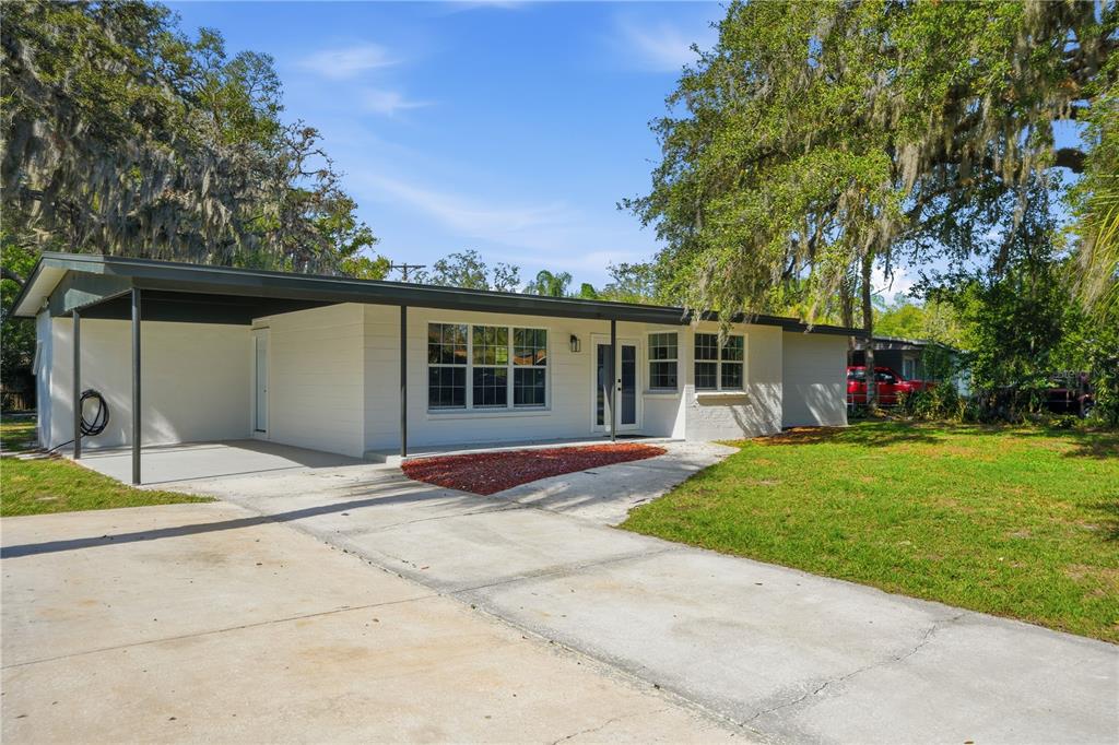 A single-story white house with a carport and a concrete driveway under large trees — 707 ABERDEEN CIRCLE, TAMPA, FL
