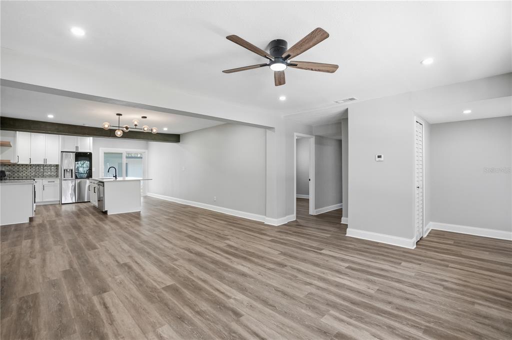 An open-concept living area features light gray walls, wood-look flooring, and an adjacent modern kitchen — 707 ABERDEEN CIRCLE, TAMPA, FL