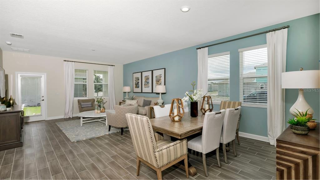A dining and living area features blue accent walls, tile flooring, and large windows — 5626 FIONA LANE, ST CLOUD, FL