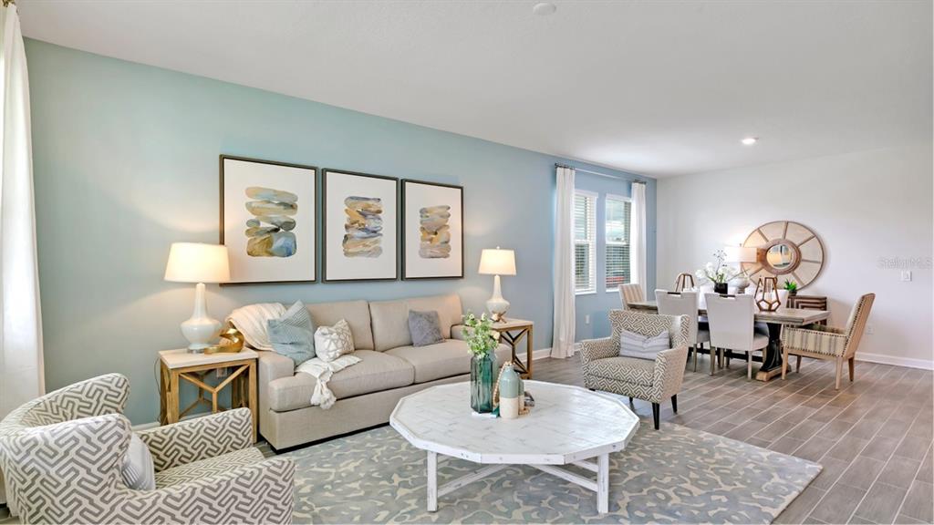 A living room and dining area feature light blue walls, neutral furniture, and tile flooring — 5626 FIONA LANE, ST CLOUD, FL