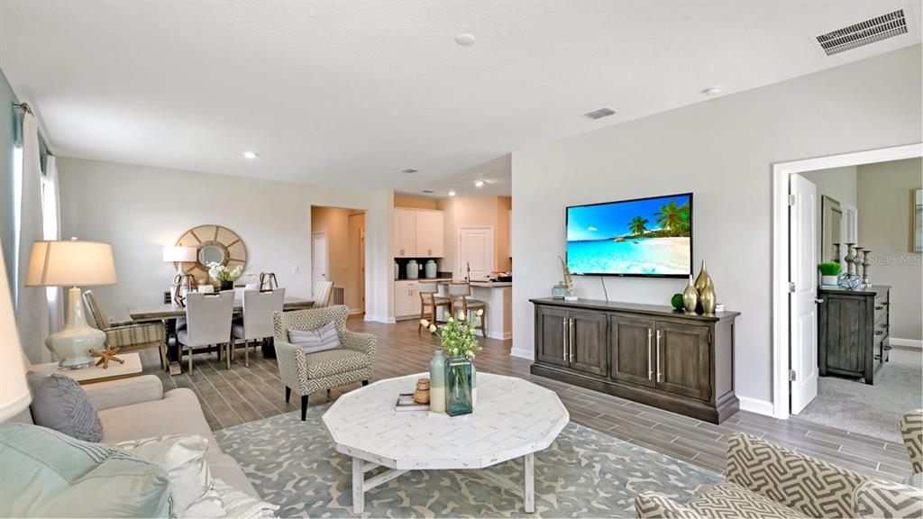 A living room with a television, a white coffee table, and an adjacent dining area — 5626 FIONA LANE, ST CLOUD, FL