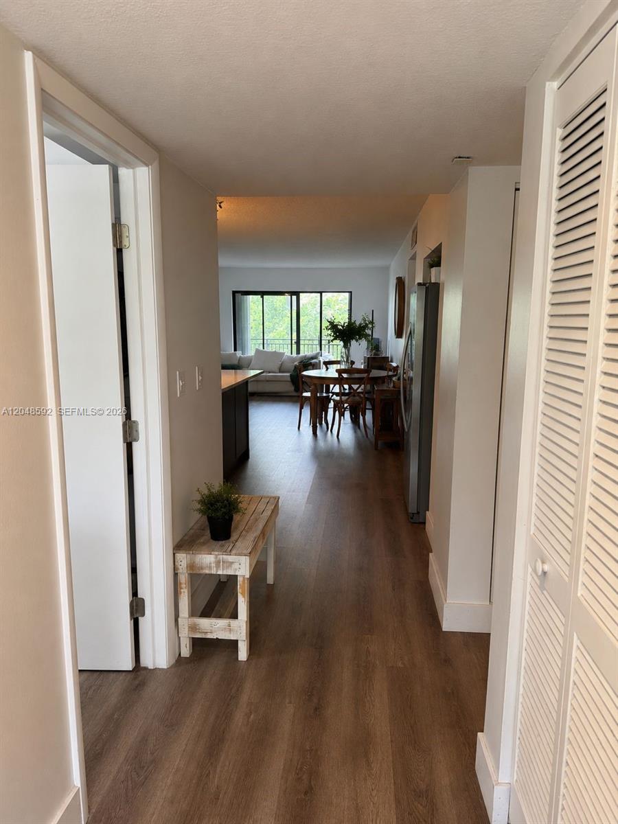 A hallway with wood-look flooring leads to an open-concept dining and living area — 16171 Blatt Blvd # 412, Weston FL 33326, WESTON, FL