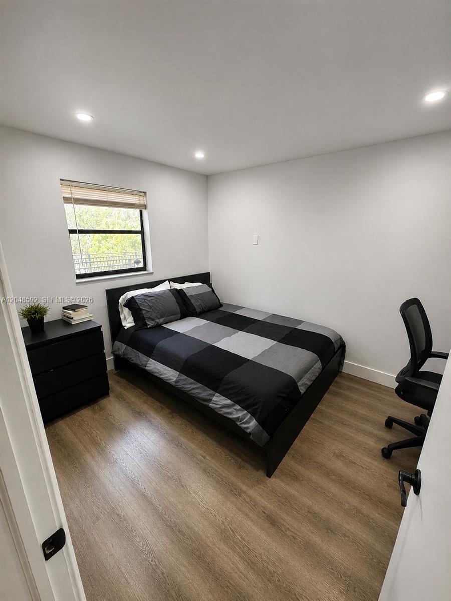 A bedroom features a bed with a plaid comforter, a nightstand, and wood-look flooring — 16171 Blatt Blvd # 412, Weston FL 33326, WESTON, FL