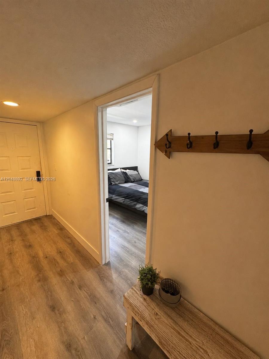 A hallway with light wood-look flooring leads to a bedroom through an open doorway — 16171 Blatt Blvd # 412, Weston FL 33326, WESTON, FL