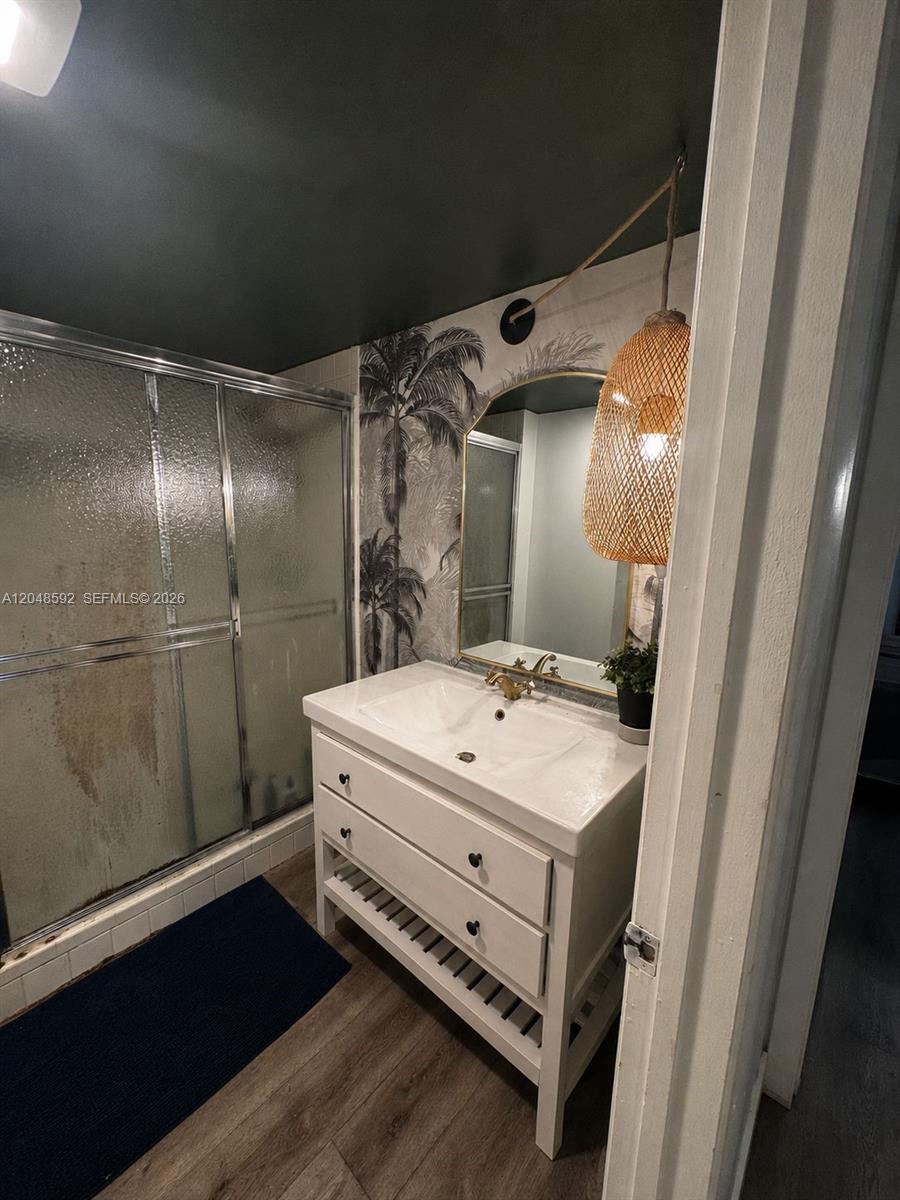 A bathroom features a white vanity, a palm-print wallpaper accent wall, and a glass shower — 16171 Blatt Blvd # 412, Weston FL 33326, WESTON, FL