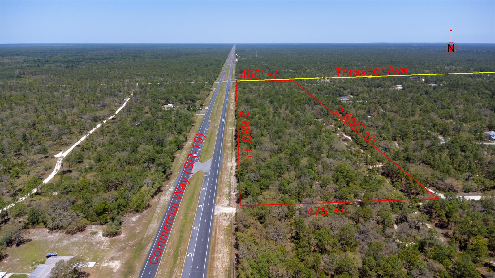 An aerial view shows a large, rectangular wooded lot outlined in red next to a highway — 0 Thrasher Avenue, FL 34614, FL