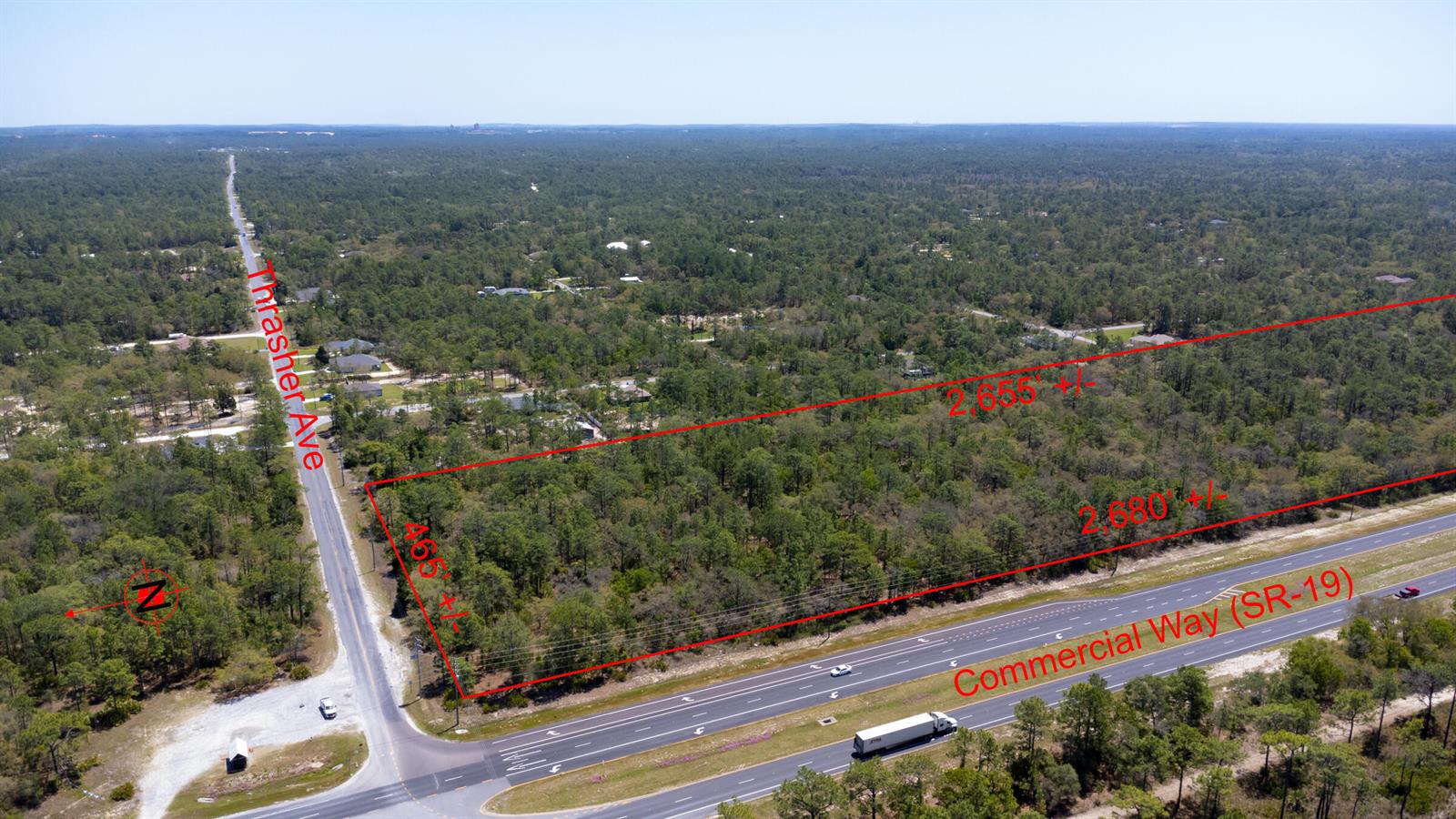 An aerial view shows a rectangular plot of undeveloped, wooded land bordering a highway — 0 Thrasher Avenue, FL 34614, FL