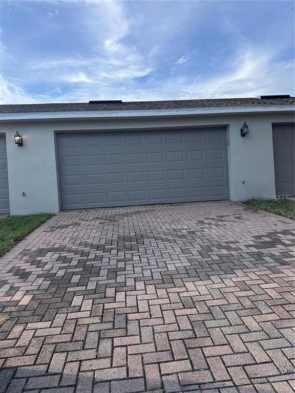 A gray garage door sits above a brick paver driveway in front of a house — 11932 DEER PATH WAY, ORLANDO, FL