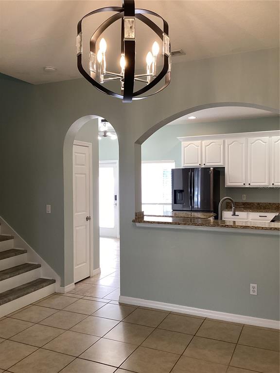 A dining area with a chandelier leads to a kitchen with white cabinets and granite countertops — 11932 DEER PATH WAY, ORLANDO, FL