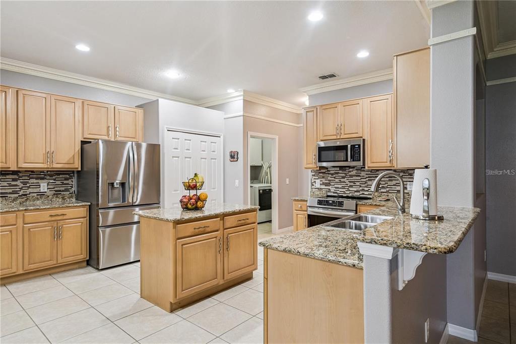 A kitchen with light wood cabinets, granite countertops, stainless steel appliances, and a center island — 480 ROB ROY DRIVE, CLERMONT, FL