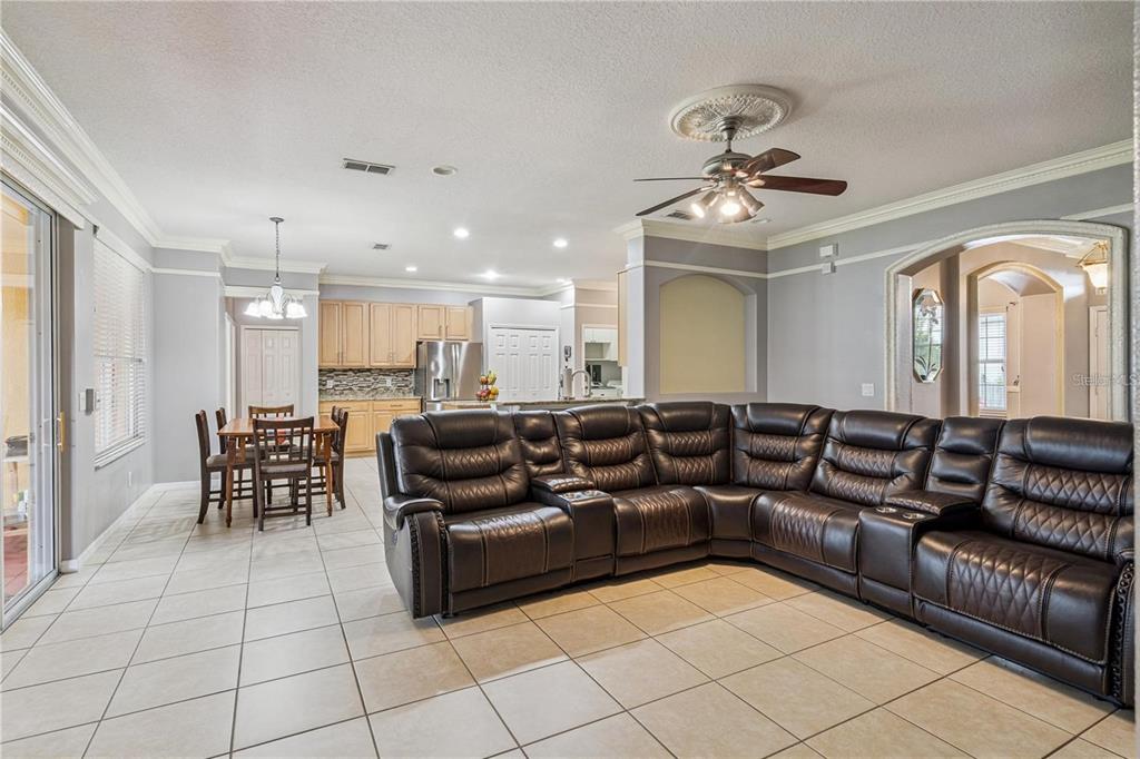 A living room with a large brown sectional sofa, tile flooring, and an open kitchen — 480 ROB ROY DRIVE, CLERMONT, FL