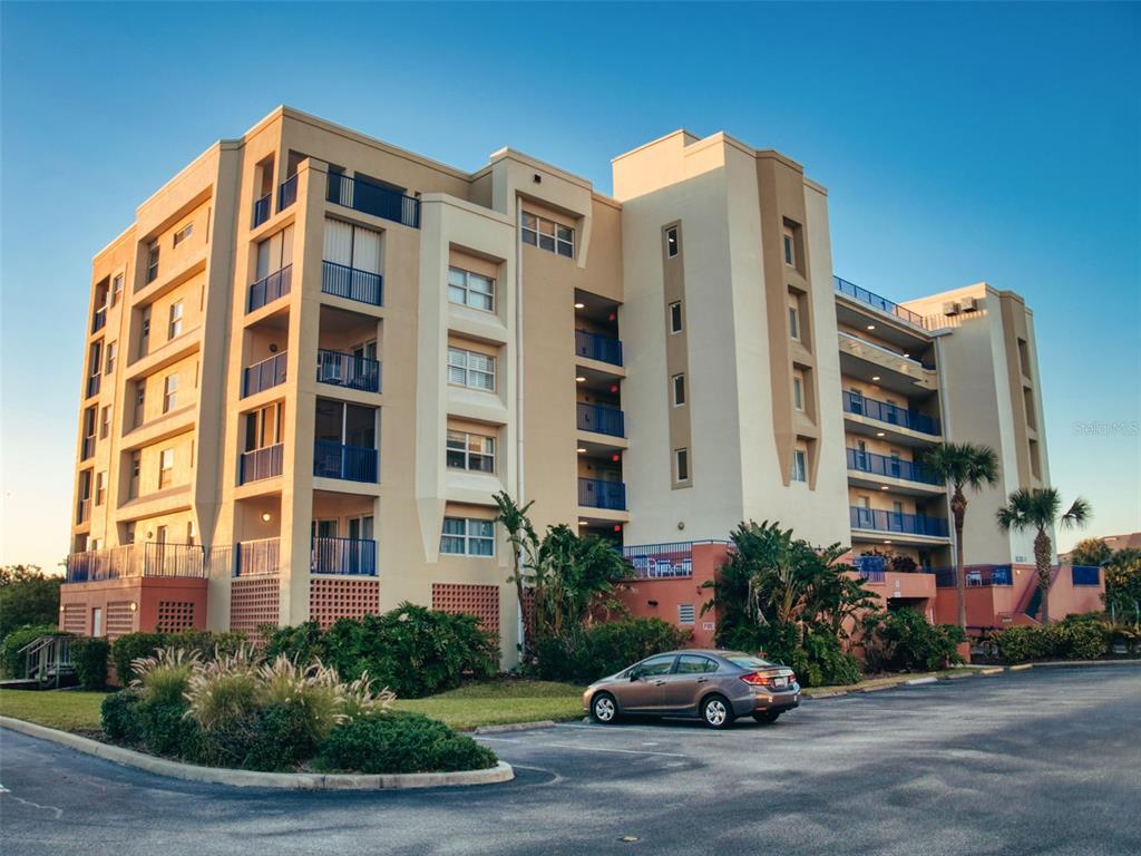 A multi-story apartment building with balconies and a parking lot in the foreground — 5300 S ATLANTIC AVENUE UNIT 4-503, NEW SMYRNA BEACH, FL