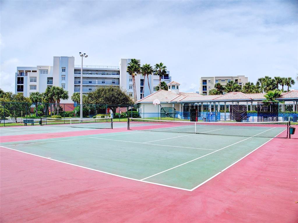 A tennis court with a green surface and red borders sits before a large building — 5300 S ATLANTIC AVENUE UNIT 4-503, NEW SMYRNA BEACH, FL