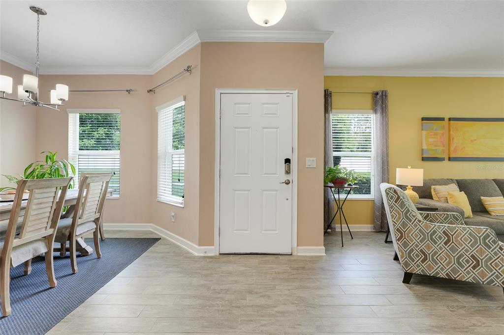 A bright entryway features light-colored tile flooring, a white front door, and adjacent dining and living areas — 3550 FAIRWATERS COURT UNIT D, CLERMONT, FL