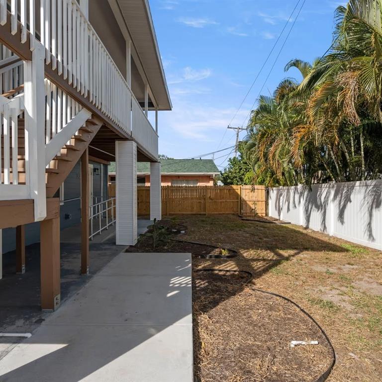 A side yard with a concrete walkway, wooden stairs, and a white vinyl privacy fence — 3103 16TH STREET N UNIT 3103, ST PETERSBURG, FL