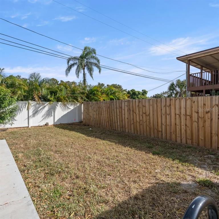 A backyard features a wooden fence, a white vinyl fence, and a palm tree — 3103 16TH STREET N UNIT 3103, ST PETERSBURG, FL
