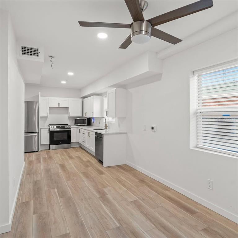 A kitchen with white cabinets, stainless steel appliances, and light wood-look flooring — 3103 16TH STREET N UNIT 3103, ST PETERSBURG, FL