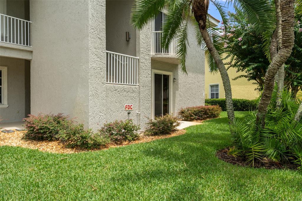 The exterior of a multi-story apartment building features a stucco facade, balconies, and an FDC connection — 6808 DALI AVENUE UNIT 101, LAND O LAKES, FL