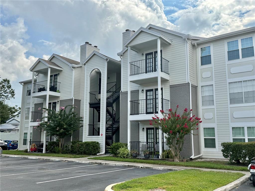 A three-story apartment building with beige siding, gray brick accents, and black metal balconies — 2550 N ALAFAYA TRAIL UNIT 3304, ORLANDO, FL