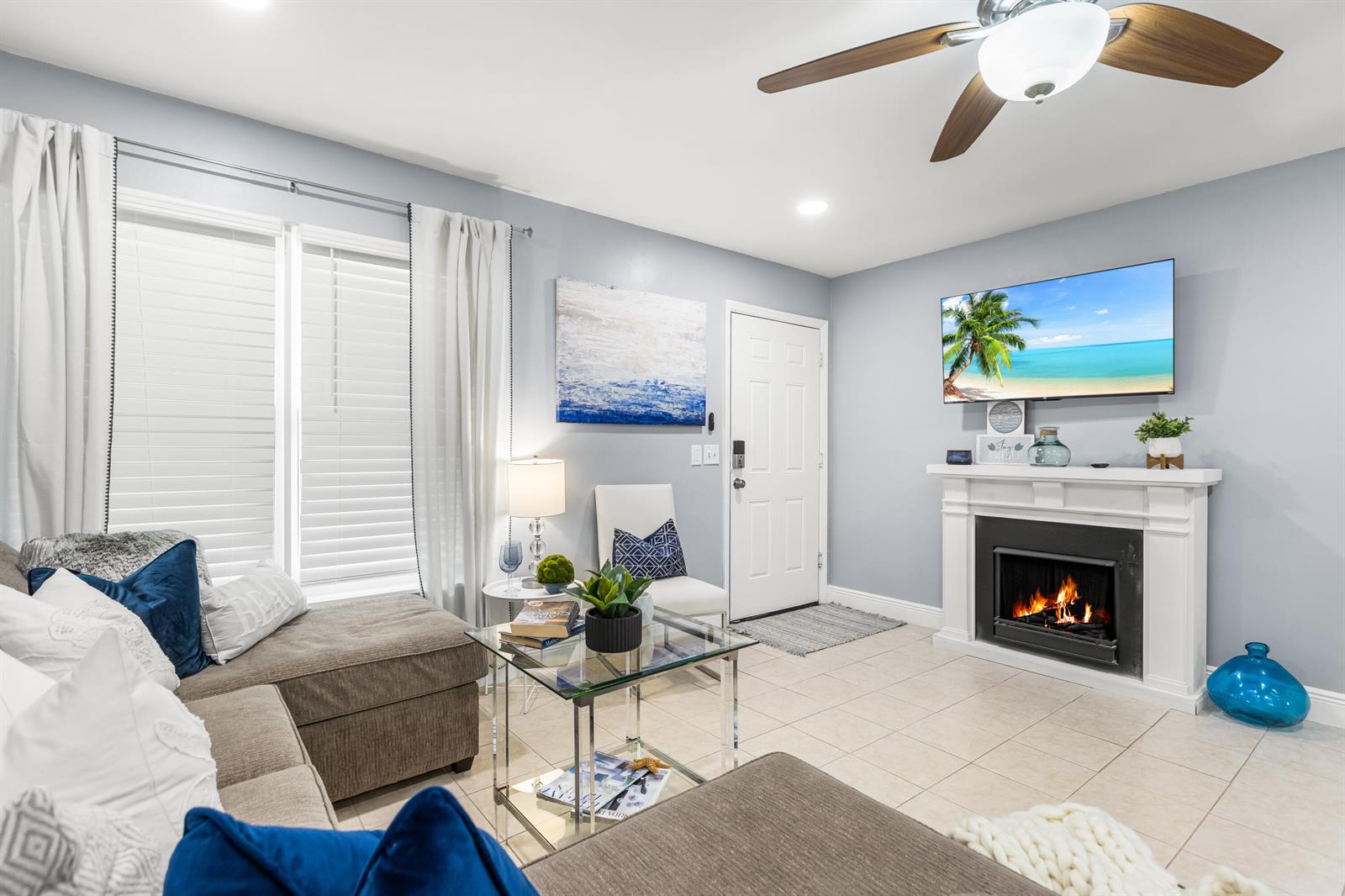 A living room features a fireplace, a wall-mounted television, a ceiling fan, and tile flooring — 4953 Bayshore Drive, Naples FL 34112, NAPLES, FL